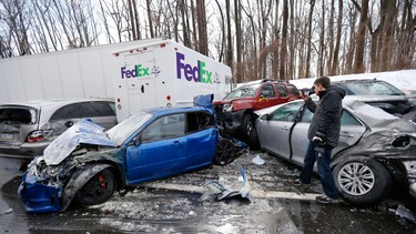 A man inspects vehicles piled up in an accident, Friday, Feb. 14, 2014, in Bensalem, Pa.