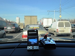 A mini camera with a  screen sits atop a dashboard of this car rolling through a street in Moscow. Dashboard video cameras play the part of digital guardian angels for Russian motorists.