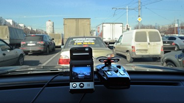 A mini camera with a  screen sits atop a dashboard of this car rolling through a street in Moscow. Dashboard video cameras play the part of digital guardian angels for Russian motorists.