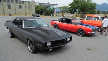 Two buddies with the two cars they built with their sons. A Black 68 Camaro and an Orange 1969 Camaro.