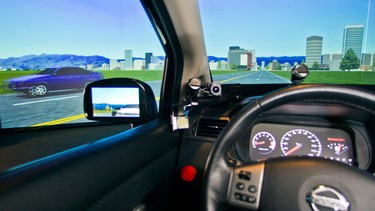 In this May 19, 2014 photo, a driving telematics simulator is demonstrated at the University of Michigan Transportation Research Institute in Ann Arbor, Mich. The wired car lets drivers navigate a simulated cityscape on a trio of screens, and will soon be reprogrammed to make it almost entirely self-driving.