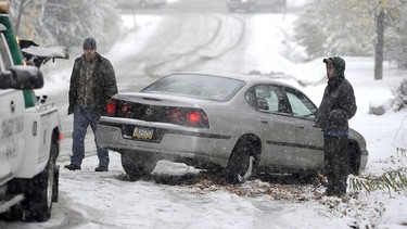 Drivers wait for a tow truck to pull their car from a ditch.