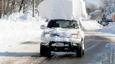 A vehicle, with a large chunk of snow on its top drives along Route 20 after digging out after a massive snow fall in Lancaster, N.Y. Wednesday, Nov. 19, 2014. Another two to three feet of snow is expected in the area.