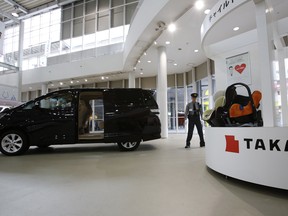 A security guard stands by child seats, manufactured and displayed by Takata Corp. at a Toyota showroom in Tokyo.