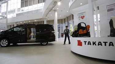 A security guard stands by child seats, manufactured and displayed by Takata Corp. at a Toyota showroom in Tokyo.