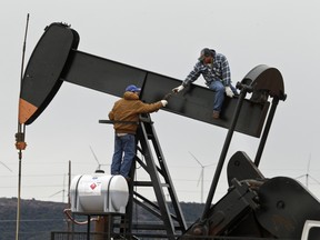 In this Tuesday, Dec. 23, 2014 photo, men work on an oil pump near Sweetwater, Texas. At the heart of the Cline, a shale formation once thought to hold more oil than Saudi Arabia, Sweetwater is bracing for layoffs and budget cuts, anxious as oil prices fall and its largest investors pull back.