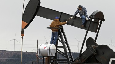 In this Tuesday, Dec. 23, 2014 photo, men work on an oil pump near Sweetwater, Texas. At the heart of the Cline, a shale formation once thought to hold more oil than Saudi Arabia, Sweetwater is bracing for layoffs and budget cuts, anxious as oil prices fall and its largest investors pull back.