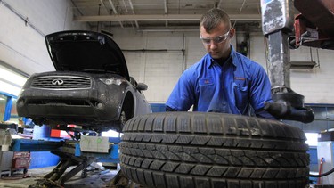 Adis Mulic, a tire technician at Kal Tire, puts snow tires on a rim at his company's shop in Calgary.