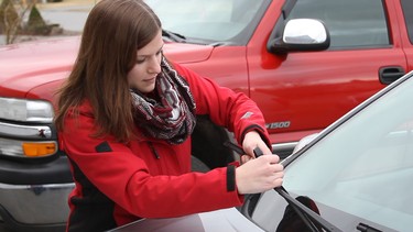 A representative with Canadian Tire installs new wiper blades on a resident's vehicle.