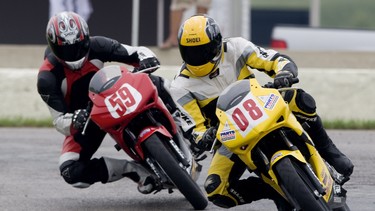 David Booth (right) races around Mosport International Raceway on a Honda CBR125R.