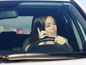 A woman talks on her phone while driving.