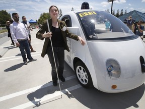 In this May 13, 2015 photo, Jessie Lorenz, of San Francisco, touches the new Google self-driving prototype car during a demonstration at the Google campus in Mountain View, Calif.  The car, which needs no gas pedal or steering wheel, will make its debut on public roads this summer.