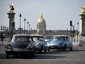 People in Citroen DS drive in front of Les Invalides in Paris on May 24, 2015 as the legendary French car celebrates its 60th anniversary.