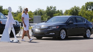 A pedestrian crosses in front of an Acura RLX as part of a demonstration at M city on its opening day Monday, July 20, 2015 at the University of Michigan campus in Ann Arbor, Mich.