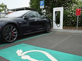 A Tesla electric-powered sedan stands at a Tesla charging station at a highway rest-stop along the A7 highway on June 11, 2015 near Rieden, Germany. Wireless charging highways and roads, if they were ever to be built on a larger scale, could help electric cars eventually take over traditional gas-powered vehicles.