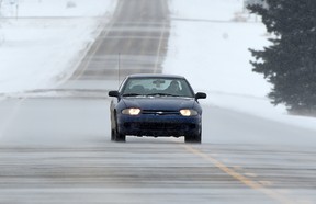 A car drives through the blowing snow on Secondary Highway 651 near Legal, Alta. on Wednesday, Feb. 11, 2015.