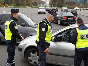 Police officers control a vehicle in Paris, Monday, March 17, 2014. Cars with even-numbered licence plates are prohibited from driving in Paris and its suburbs Monday, following a government decision over the weekend.  Paris is taking drastic measures to combat its worst air pollution in years, banning around half of the city's cars and trucks from its streets in an attempt to reduce the toxic smog that's shrouded the City of Light for more than a week. Visible in background is the Arc de Triomphe.