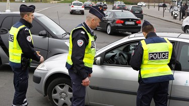 Police officers control a vehicle in Paris, Monday, March 17, 2014. Cars with even-numbered licence plates are prohibited from driving in Paris and its suburbs Monday, following a government decision over the weekend.  Paris is taking drastic measures to combat its worst air pollution in years, banning around half of the city's cars and trucks from its streets in an attempt to reduce the toxic smog that's shrouded the City of Light for more than a week. Visible in background is the Arc de Triomphe.