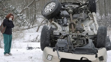 Carrie Miller, 25, looks at her wrecked, overturned vehicle following a 25-vehicle chain-reaction crash on Interstate 79 just north of Edinboro, Pa., on Thursday, Feb. 27, 2014, at about 9 a.m. in Franklin Township. Miller said white-out conditions caused by a heavy snow squall caused the accident.