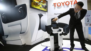 Akifumi Tamaoki, general manager of Toyota's partner robot division, demonstrates HSR, or Human Support Robot, at the International Robot exhibition in Tokyo. HSR can pick up after people, bring an item to the bedside or open curtains.