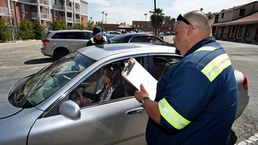 Staff check a woman's vehicle for road-worthiness after she signed up to become an Uber driver at the first of Uber's 'Work On Demand' recruitment events where they hope to sign 12,000 new driver-partners, in South Los Angeles on March 10, 2016.