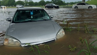 Vehicles slowly drive past a flooded car near an exit ramp on Interstate 49 in Grand Coteau, La. as flash floods swept through the area Sunday, May 1, 2016.