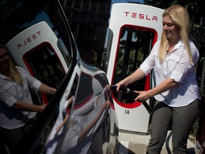 Alexis Georgeson demonstrates how to charge a Tesla model S electric car during a ribbon-cutting for Tesla's first Ontario supercharger stations in Toronto , Ontario, Thursday,September 4, 2014.