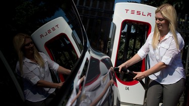 Alexis Georgeson demonstrates how to charge a Tesla model S electric car during a ribbon-cutting for Tesla's first Ontario supercharger stations in Toronto , Ontario, Thursday,September 4, 2014.