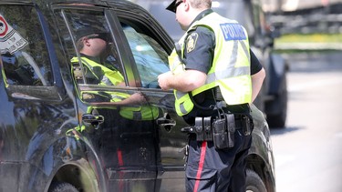 A police officer hands out a ticket to a motorist during a distracted driving blitz on Tuesday, May 17, 2016 near the Midtown Bridge in Winnipeg, Manitoba.