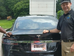In this 2015 photo provided by his neighbor, Krista Kitchen, Joshua Brown stands by his new Tesla electric car near his home in Canton, Ohio. Brown died in an accident in Florida on May 7, 2016 in the first fatality from a car using self-driving technology. According to statements by the government and the automaker, his vehicle's cameras didn't make a distinction between the white side of a turning tractor-trailer and the brightly lit sky while failing to automatically activate its brakes.
