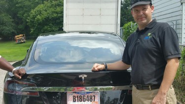 In this 2015 photo provided by his neighbor, Krista Kitchen, Joshua Brown stands by his new Tesla electric car near his home in Canton, Ohio. Brown died in an accident in Florida on May 7, 2016 in the first fatality from a car using self-driving technology. According to statements by the government and the automaker, his vehicle's cameras didn't make a distinction between the white side of a turning tractor-trailer and the brightly lit sky while failing to automatically activate its brakes.