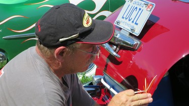 Pinstriper Rollie Guertin applies a design to Driving contributor Jil McIntosh's 1947 Cadillac. The intricate designs were popular add-ons for traditional hot rods and custom cars.