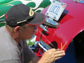 Pinstriper Rollie Guertin applies a design to Driving contributor Jil McIntosh's 1947 Cadillac. The intricate designs were popular add-ons for traditional hot rods and custom cars.