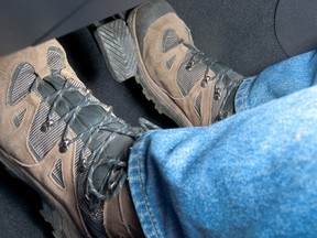 A driver wearing hiking boots 'rides the clutch' by stepping on the gas and clutch pedals at the same time.