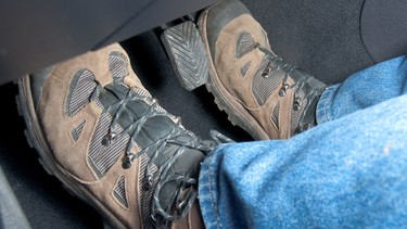 A driver wearing hiking boots 'rides the clutch' by stepping on the gas and clutch pedals at the same time.