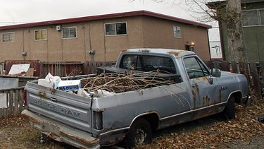 A rusting, unplated pickup truck sits in a Forest Lawn back alley filled with debris.