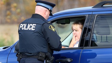 In this file photo, Ontario Provincial Police Const. Mike Primeau speaks to Jackie Lacroix, after he pulled the driver over for talking on her cellphone while driving