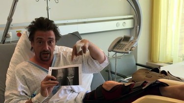This handout video screengrab released by Drivetribe and Amazon on June 11, 2017, shows British television presenter Richard Hammond gesturing towards an x-ray of his injured knee as he sits in a hospital room in St Gallen, after he was involved in a car accident while filming in Switzerland.