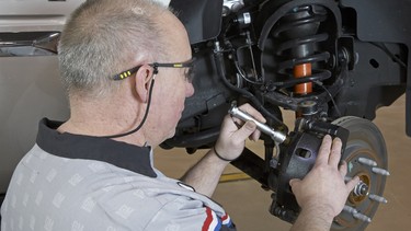 A technician checks the front brake system during a vehicle inspection.