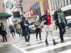 Pedestrians make their way across a wet crosswalk in London, Ontario.