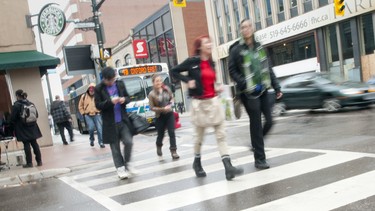 Pedestrians make their way across a wet crosswalk in London, Ontario.