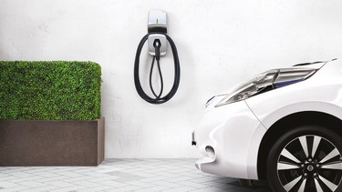 A Nissan Leaf parked next to a home charger.