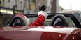 Santa waiving from his red deliviery car