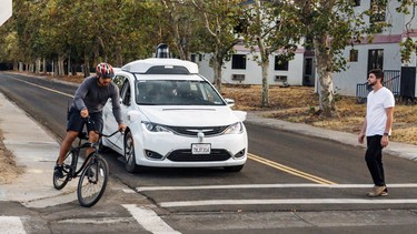 A Chrysler Pacifica minivan equipped with Waymo's self-driving car technology, being tested with the company's employees as a biker and a pedestrian at Waymo's facility in Atwater, Calif.