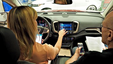 Driving journalists Lorraine Sommerfeld, left, and David Booth trying out the GMC IntelliLink infotainment system at Centennial College in Scarborough, Ontario.