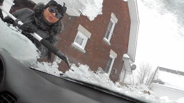Justine Viray-Levac scraps off her front windshield after  freezing rain in Cornwall, Ont.