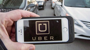 A person holds a mobile phone with the Uber app showing on it.