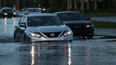 In this file photo, cars make their away through a flooded street the morning after Hurricane Irma swept through the area on September 11, 2017 in Bonita Springs, Florida. Generally, driving through flooded roads is a bad idea. But if you have to, take it slow.