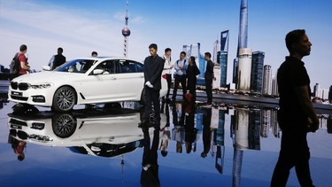 In this April 19, 2017, file photo, visitors look at the BMW 5 series vehicle displayed at the Auto Shanghai 2017 show at the National Exhibition and Convention Center in Shanghai, China.