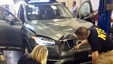 In this March 20, 2018, file photo provided by the National Transportation Safety Board, investigators examine a driverless Uber SUV that fatally struck a woman in Tempe, Ariz. In a preliminary report on the crash released Thursday, May 24, federal investigators said the autonomous Uber SUV that struck and killed an Arizona pedestrian in March spotted the woman about six seconds before hitting her, but didn’t stop automatically because emergency braking was disabled.